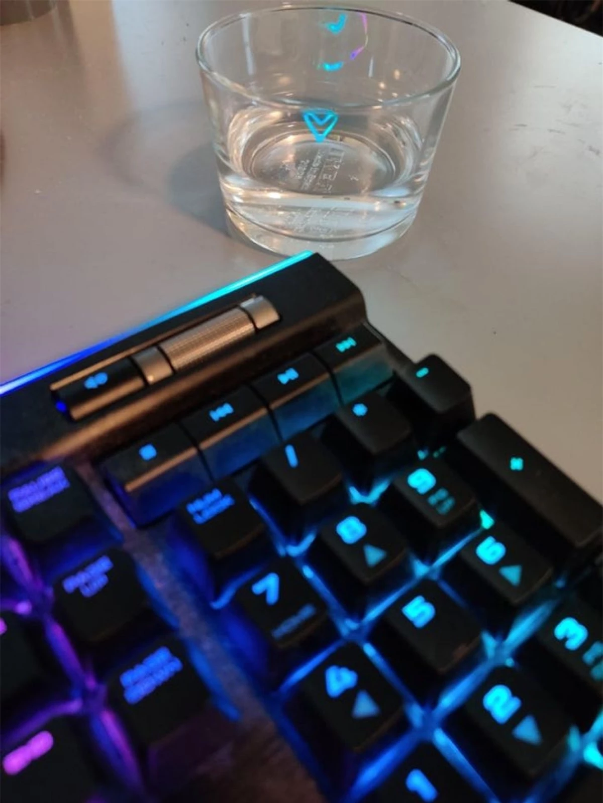 Ánh đèn từ bàn phím máy tính tạo thành hình trái tim nhỏ xinh trên chiếc cốc uống nước.