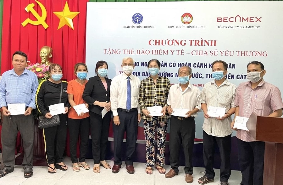 Ông Phạm Ngọc Thuận, Tổng Giám đốc Becamex IDC trao tặng thẻ Bảo hiểm y tế cho người dân.