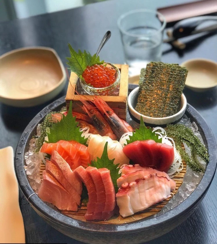 Sashimi là món ăn truyền thống của người dân xứ sở mặt trời mọc. Món ăn được làm từ hải sản tươi sống như cá hồi, sò đỏ, bạch tuộc... cắt thành lát mỏng, bài trí đẹp mắt cùng các loại rau, hoa. Sashimi thường dùng kèm nhiều loại gia vị như nước tương, mù tạt, gừng đỏ, lá tía tô, bạc hà, củ cải vàng... Món ăn chinh phục thực khách cả về phần nhìn lẫn hương vị. Ảnh: Sorae Sushi Sake Lounge.