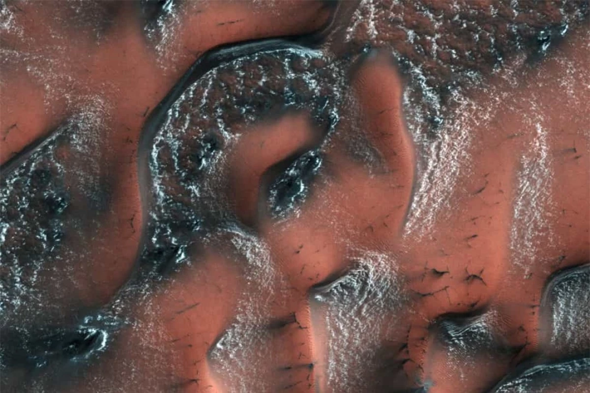 Những đụn cát ở bán cầu bắc của sao Hỏa được bao phủ bởi băng tuyết cho tới khi ánh nắng mùa xuân chiếu xuống khiến những lớp băng tan ra, để lộ lớp cát tối màu bên dưới những đụn cát.