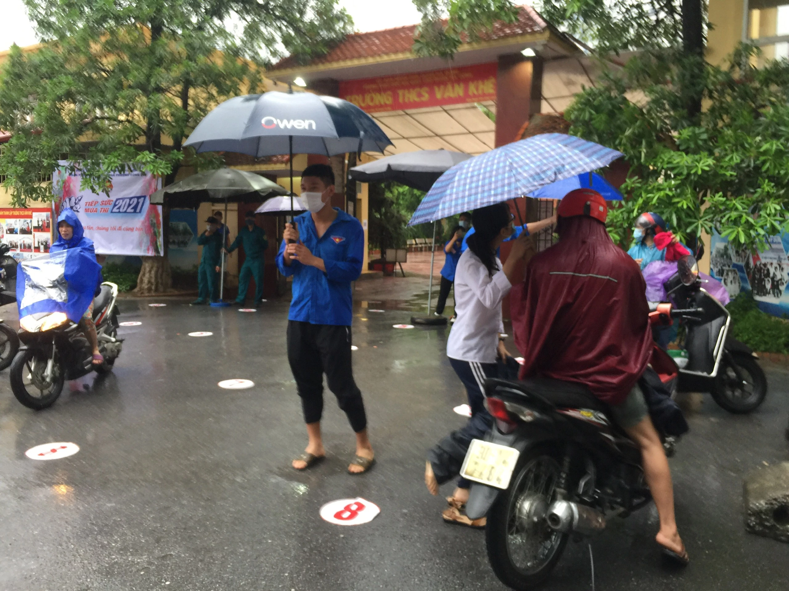 Từ sáng sớm, đội tình nguyện viên đã sẵn sàng hỗ trơ thí sinh từ ngoài cổng trường vào phòng thi để không bị ướt.