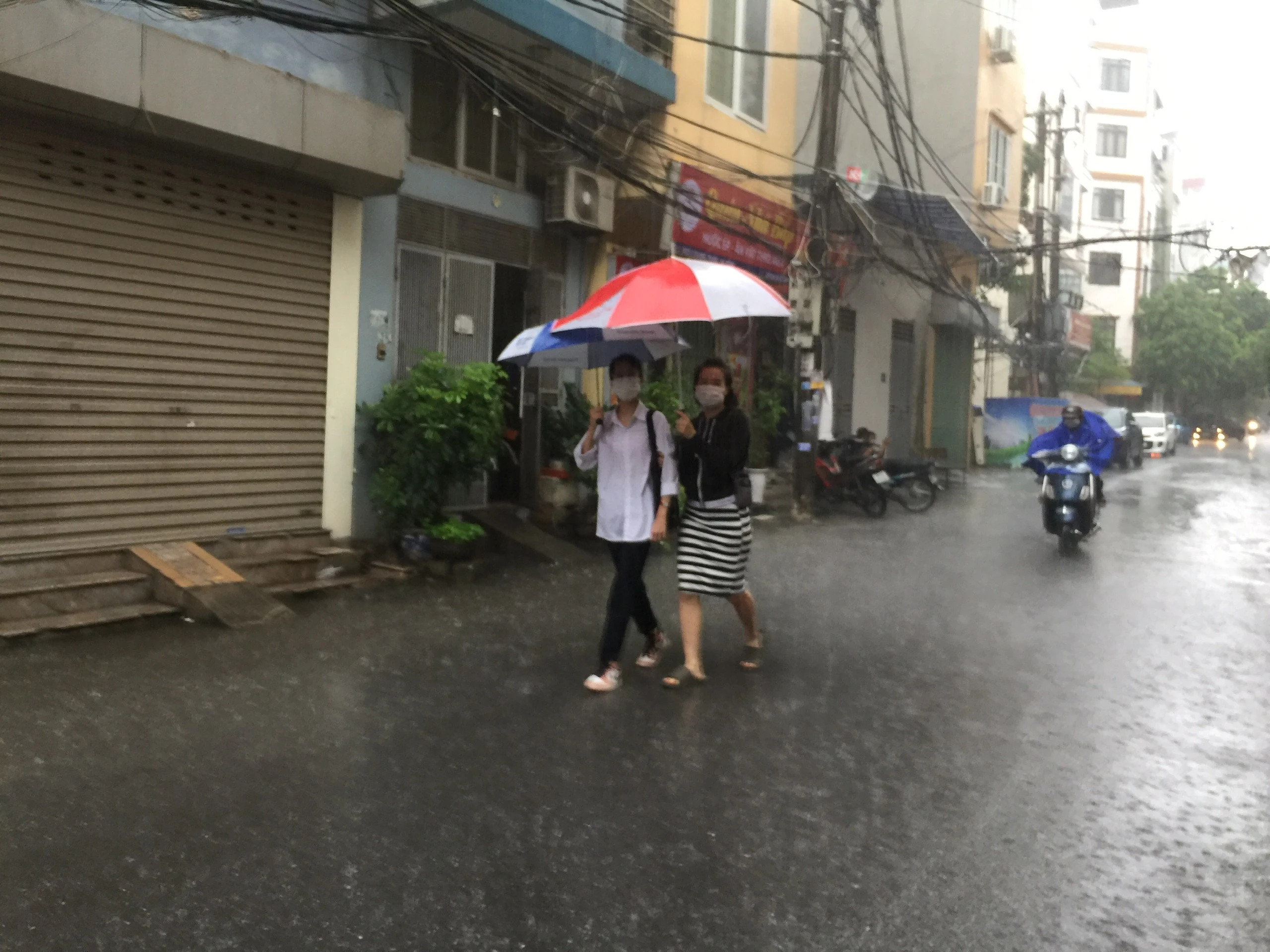 Phụ huynh đưa con đi thi dưới cơn mưa nặng hạt tại điểm thi THPT Quang Trung - Hà Đông.