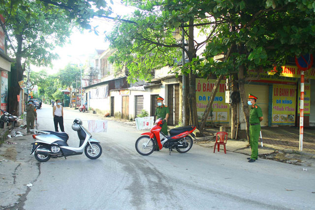 Lực lượng chức năng tiến hành phong tỏa, chốt chặn tại các ngõ thuộc khối 4, phường Hà Tập, khu vực bệnh nhân sinh sống (Ảnh: TTXVN)