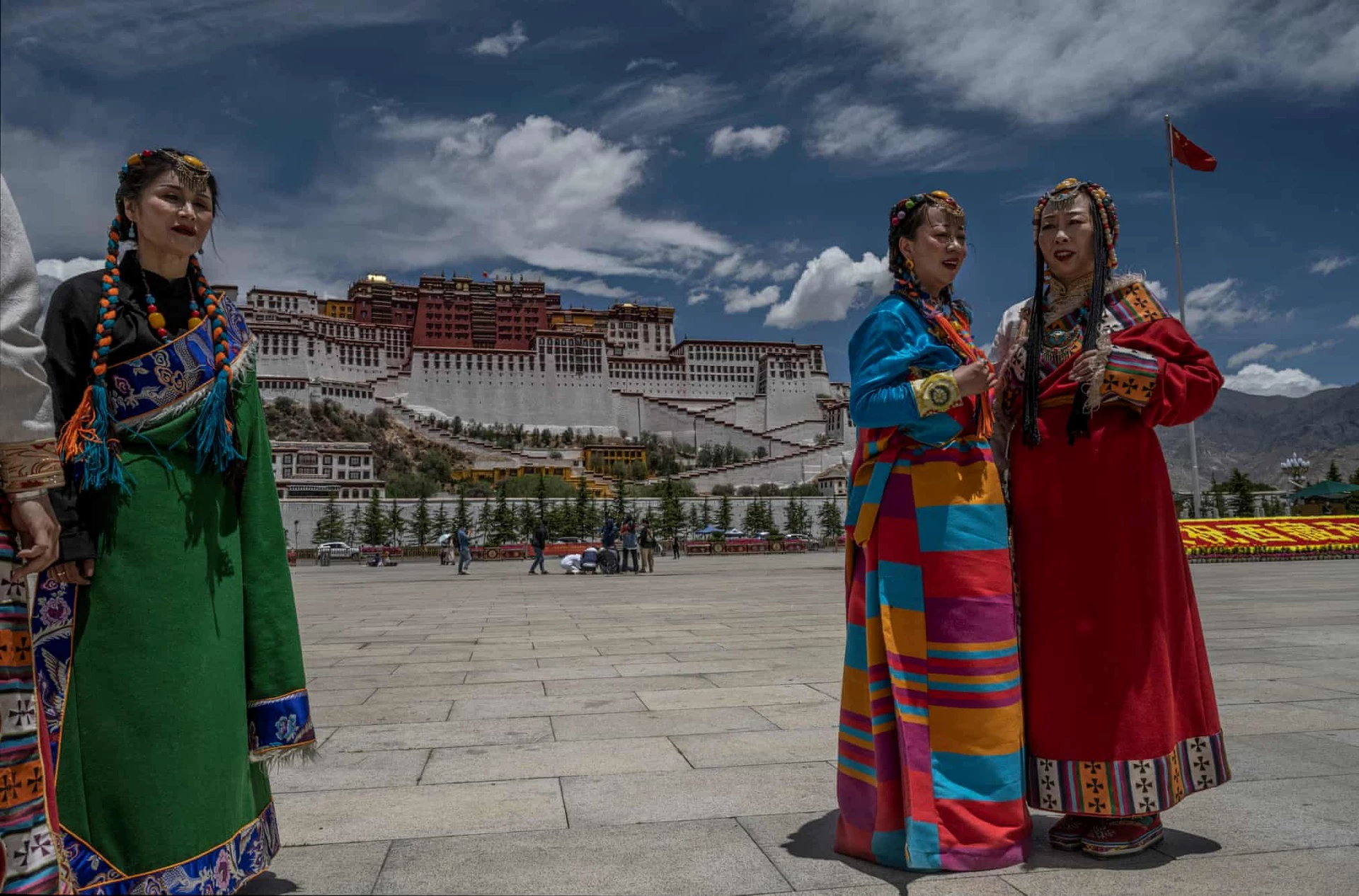 Các cô gái trong bộ trang phục truyền thống đứng trước điện Potala. Chuba, loại áo khoác làm từ da cừu, khá phổ biến với những người du mục.