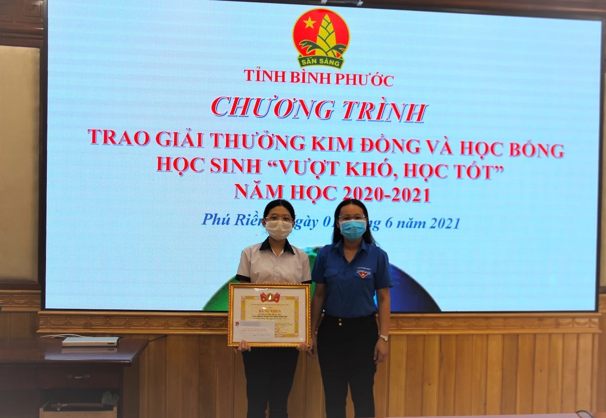 Chị Lê Thị Hồng Phấn, Phó Bí thư Tỉnh Đoàn, Chủ tịch Hội đồng Đội tỉnh (bìa phải) trao giải thưởng Kim Đồng cho em Phạm Thị Xuân Mai, học sinh lớp 9a5, trường THCS Long Hưng, huyện Phú Riềng