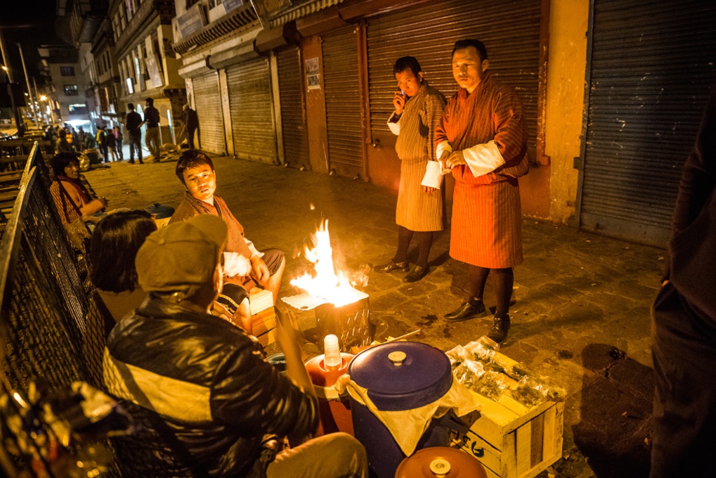 Những người bán hàng rong sưởi ấm bên đống lửa trên phố. Thủ đô của Bhutan nằm ở độ cao 2.320 m, dù trong mùa hè, nhiệt độ vẫn xuống thấp vào ban đêm.