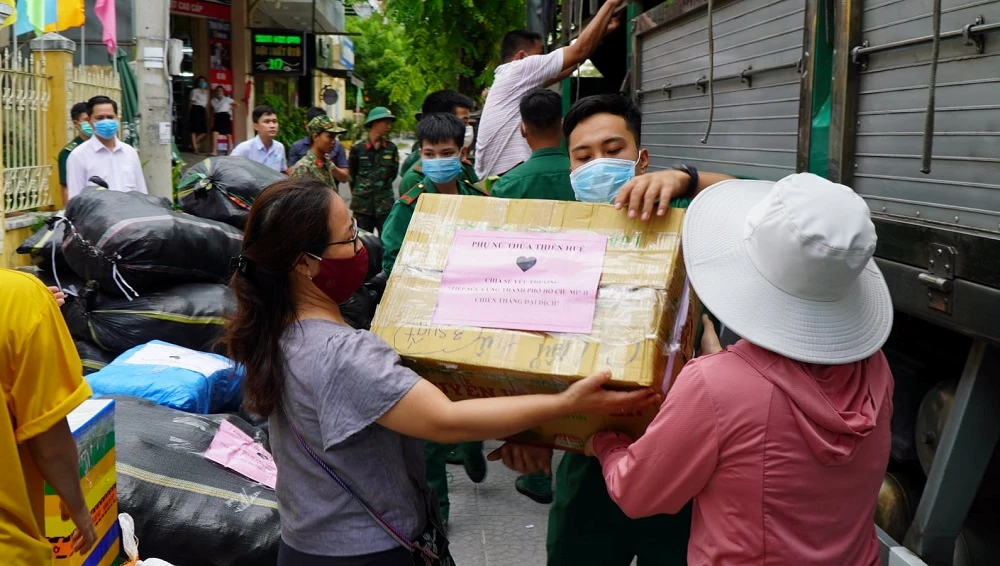 Người dân và lực lượng vũ trang cùng nhau vận chuyển lương thực, hàng hoá lên xe.