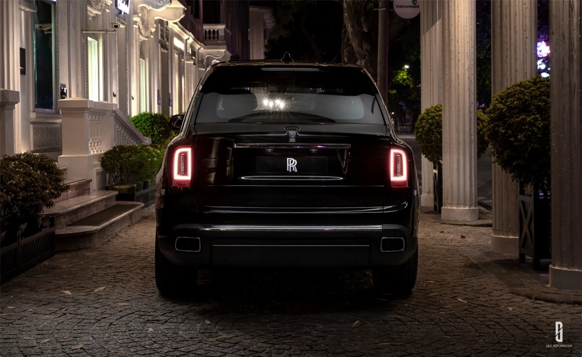 Trong màn đêm trên đường phố Hà Nội, Rolls-Royce Cullinan màu đen nổi bật với cụm đèn hậu, hai ống xả đặt ở vị trí cân đối.