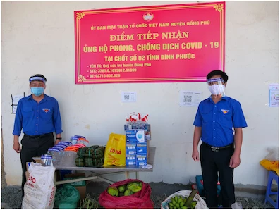 Bí thư Tỉnh Đoàn Trần Quốc Duy (bên phải) trao tặng rau, củ, quả tại chốt kiểm soát giao thông số 2 của tỉnh tại xã Tân Lập (H.Đồng Phú)
