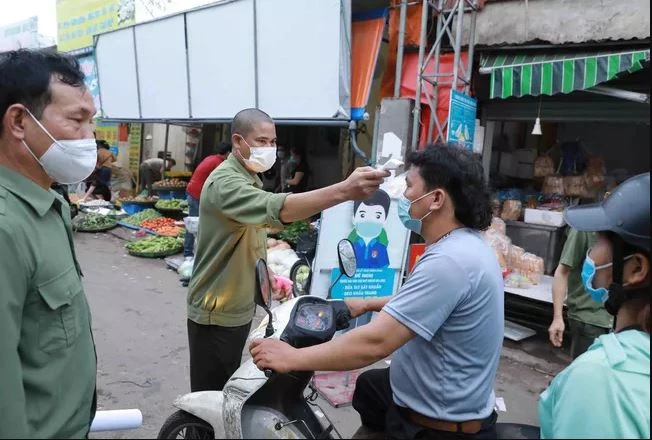 Ban Quản lý chợ đầu mối Minh Khai tổ chức đo thân nhiệt cho người dân khi đến chợ. Ảnh: TTXVN