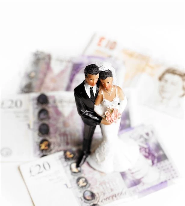 0_Bride-and-groom-wedding-figures-standing-on-a-pile-of-banknotes-Concept-of-the-cost-of-weddingspre.jpg