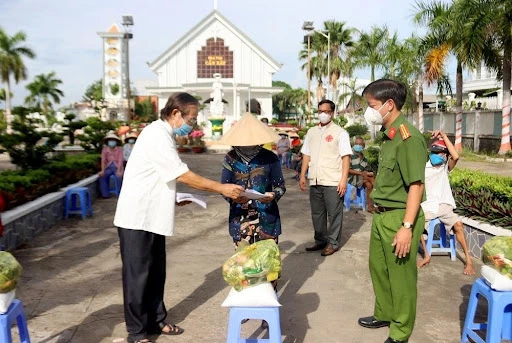 Trung tá Nguyễn Đức Hậu, Trưởng Công an TP Long Xuyên cùng Linh mục Trần Văn Khoa, Chánh xứ Giáo xứ Cần Xây tặng quà cho bà con giáo dân tại P Bình Đức.