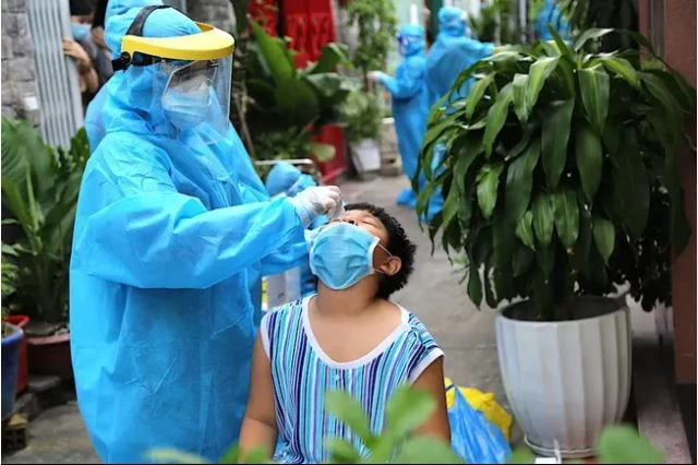 Cán bộ y tế TP Hồ Chí Minh lấy mẫu xét nghiệm cho một trẻ em tại cộng đồng. Ảnh: PLO.