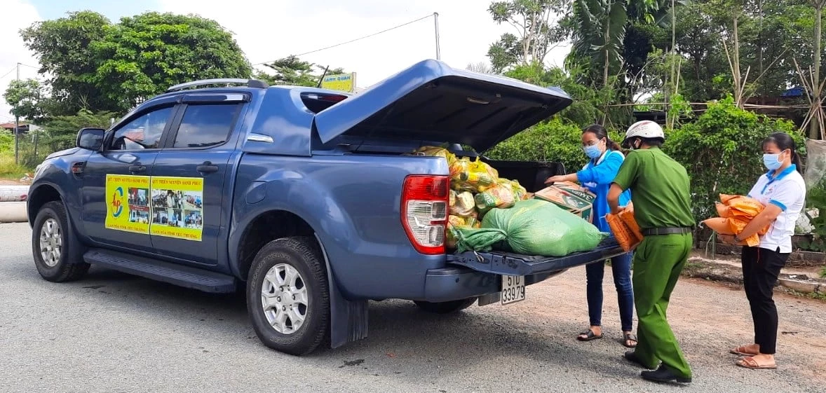 Các thành viên thuộc Quỹ Thiện nguyện Hạnh Phúc (TP Hồ Chí Minh) đang cùng lực lượng thực hiện nhiệm vụ chống dịch vận chuyển túi an sinh từ Bình Phước xuống xe để trao cho người dân P. Phước Long B (TP Thủ Đức)