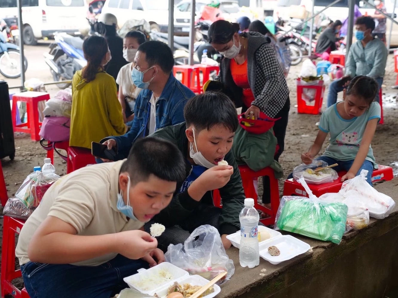 Những đứa trẻ ngồi ăn thật ngon lành sau khi nhận các suất ăn miễn phí từ Tỉnh Đoàn và CLB Sen Hồng tại “nhà chờ” ở chốt phòng chống dịch số 2 (H. Đồng Phú)
