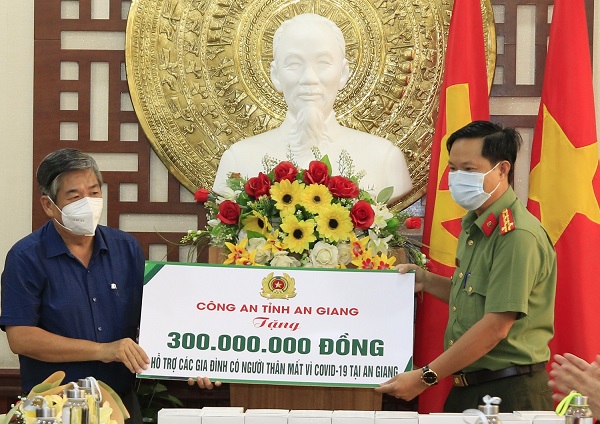 Công an tỉnh (Bìa phải) trao bảng tượng trưng hỗ trợ tiền cho Đại diện Mặt trận Tổ quốc Việt Nam tỉnh.