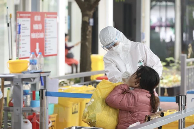 Nhân viên y tế bệnh viện Thanh Nhàn, Hà Nội, lấy mẫu xét nghiệm COVID-19 cho người đến khám có triệu chứng. (Ảnh: TTXVN)