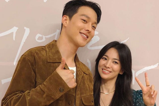 Jang Ki Yong phục vụ Song Hye Kyo như nữ vương, đi phía sau cẩn thận che ô cho đàn chị