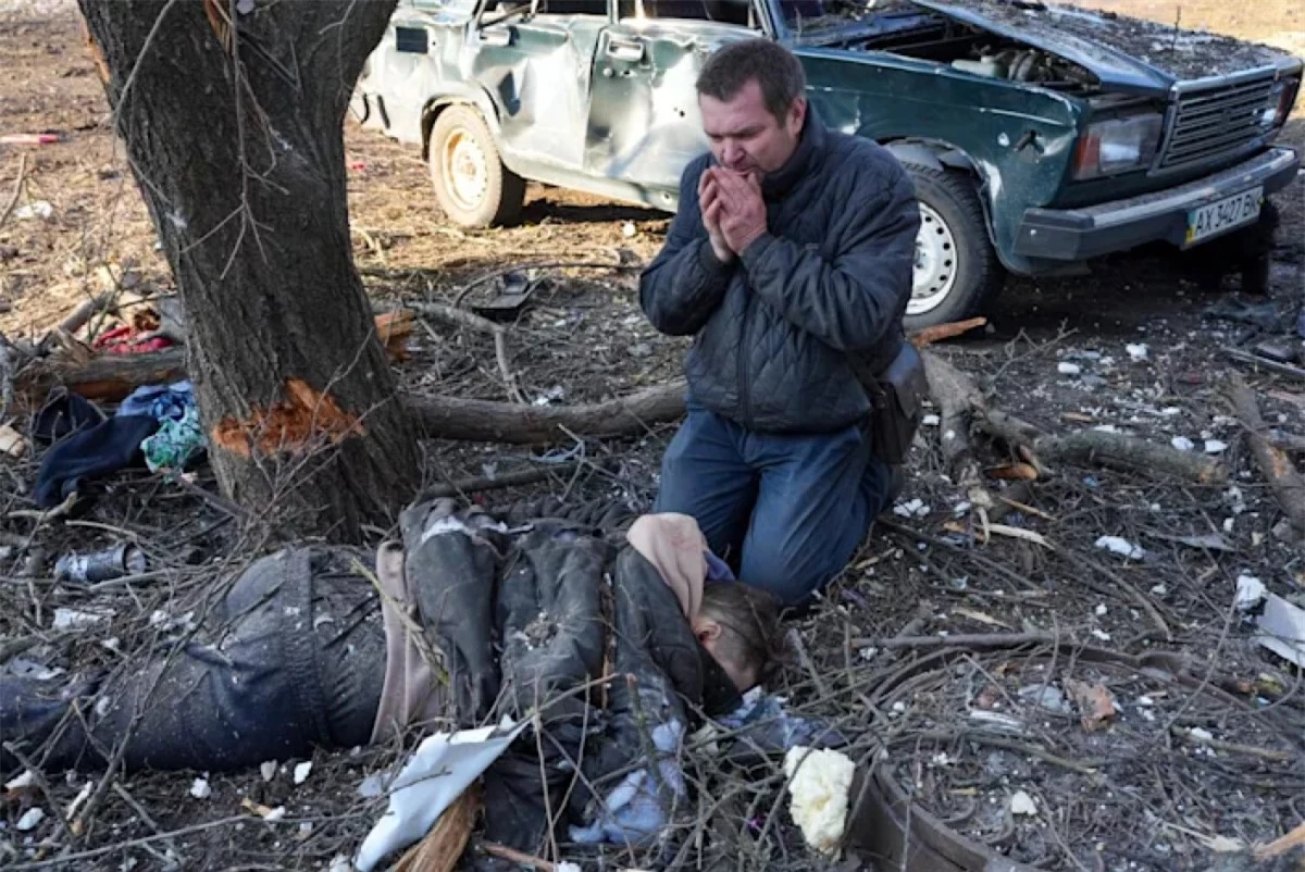 Một người đàn ông bật khóc trước bên cạnh một thi thể sau vụ không kích ở ngoại ô Kharkiv, Ukraine. (Ảnh:Anadolu Agency)