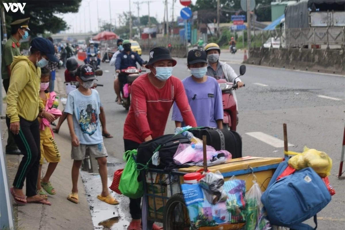 Một gia đình đi bộ, đẩy xe chất đầy hành lý về quê. (Ảnh: Tỷ Huỳnh, Lê Minh)