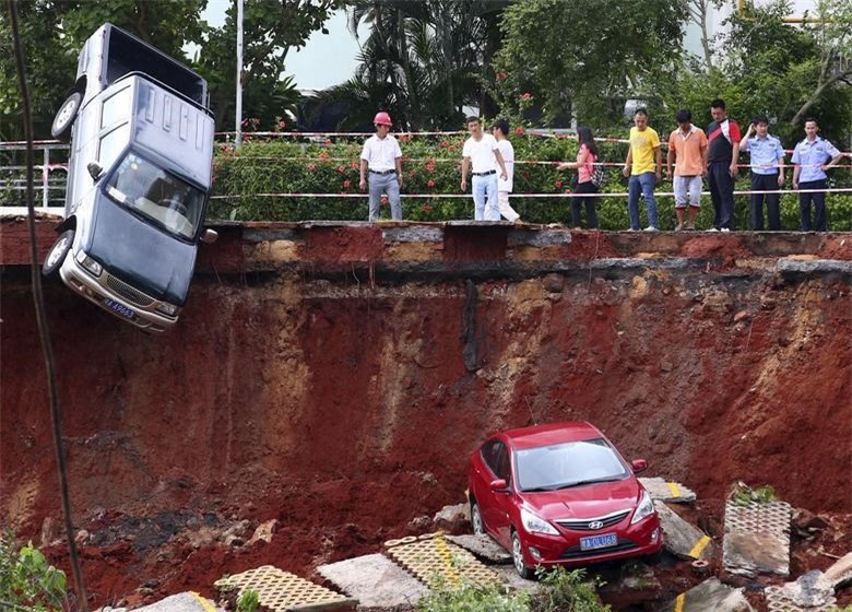 Người d&acirc;n tập trung chứng kiến cảnh tượng loạt xe hơi bị mắc kẹt dưới "hố tử thần" tại một b&atilde;i đậu xe sau trận mưa lớn đổ xuống Hải Khẩu, tỉnh Hải Nam, Trung Quốc v&agrave;o ng&agrave;y 16/9/2015. Ảnh: Reuters.