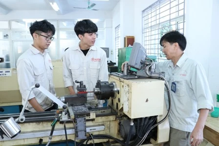 Thầy giáo Nguyễn Phan Huấn (bên phải) hướng dẫn thực hành nghề Cắt gọt kim loại cho học sinh hệ đào tạo 9+