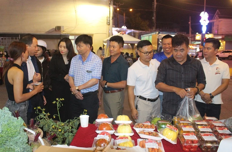 Các đại biểu và du khách tham quan các gian hàng nông sản hữu cơ, sản phẩm OCOP trưng bày tại phiên chợ.