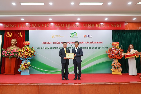 GS.TS Lê Quân (bên phải) trao kỷ niệm chương vì sự nghiệp phát triển ĐHQGHN cho doanh nhân Đỗ Quang Hiển.