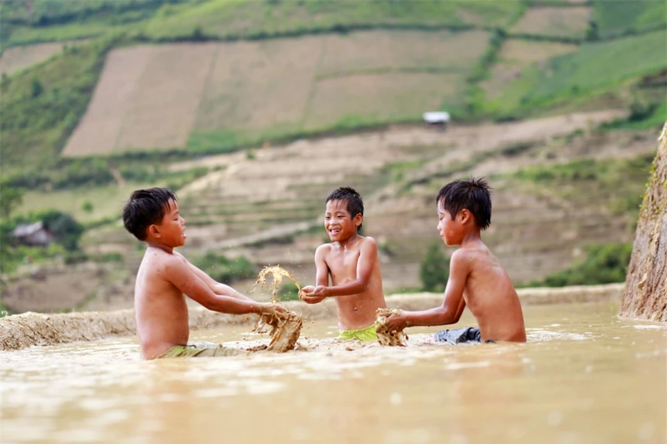 Những đứa trẻ người M&ocirc;ng tranh thủ chơi đ&ugrave;a b&ecirc;n những thửa ruộng bậc thang đ&atilde; được đổ nước.