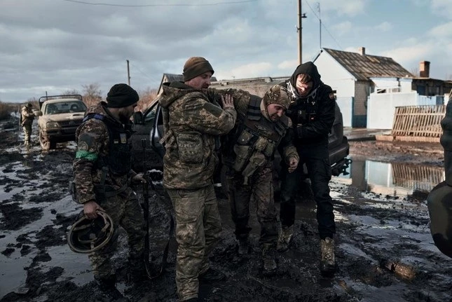 Lính Ukraine giúp đồng đội lên một chiếc xe cứu hộ ở chiến trường Bakhmut ngày 20/2. (Ảnh: AP)