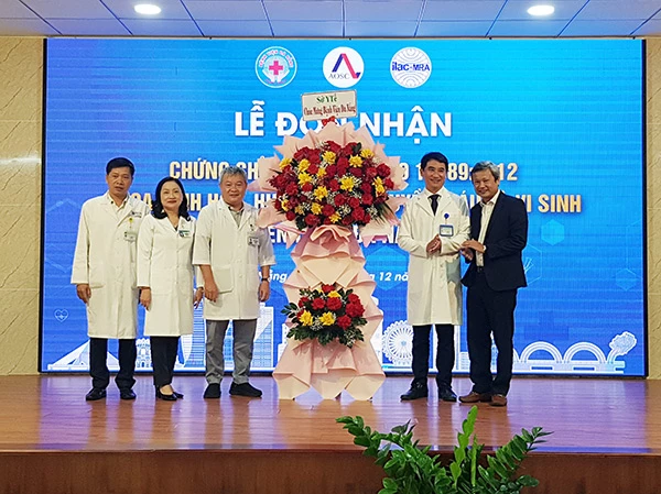 BS.CKII Võ Xuân Phúc (bìa phải) thay mặt lãnh đạo Sở Y tế tặng hoa chúc mừng Bệnh viện Đà Nẵng đạt chứng chỉ xét nghiệm quốc tế ISO 15189.