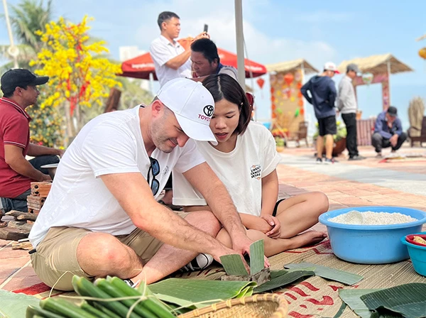 Du khách trải nghiệm gói bánh chưng trong chương trìnhh "Xuân yêu thương" bên bãi biển Đà Nẵng.