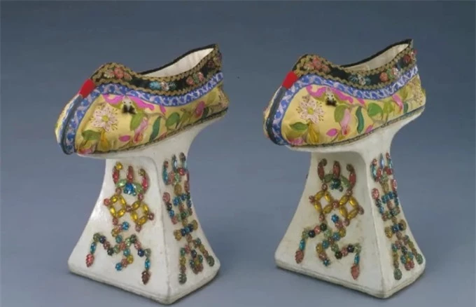 Một đôi giày đế “chậuhoa” từ thời Quảng Tự, phía dưới làm bằng gỗ, bọc vải trắng, sơn bằng bột màu trắng và khảm đá