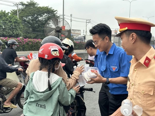 Cảnh sát giao thông phát nước, khăn lạnh miễn phí hỗ trợ người dân về quê đón Tết - Ảnh 1.