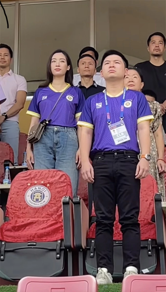 Hoa hậu Đỗ Mỹ Linh cùng chồng chủ tịch CLB Hà Nội - Đỗ Vinh Quang mặc áo tím truyền thi đấu của đội bóng thủ đô xuất hiện trên khán đài sân Hàng Đẫy tối ngày 30/6