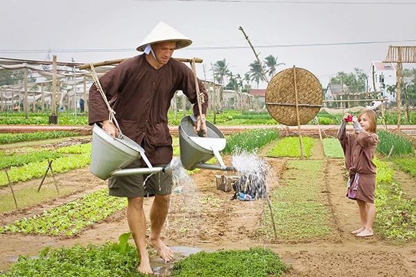 Du khách nước ngoài trải nghiệm nghề trồng rau tại làng rau Trà Quế.