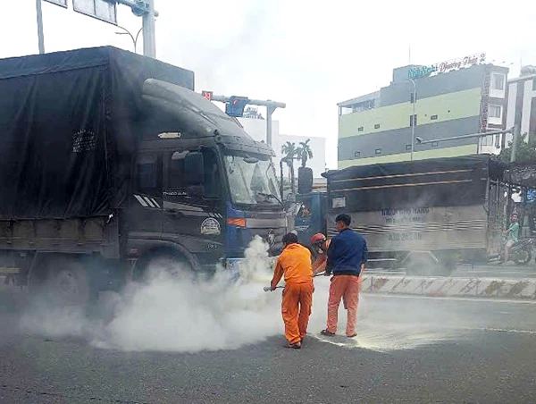 Các công nhân Điện lực Liên Chiểu dùng bình chữa cháy của đơn vị dập tắt đám cháy do vụ tai nạn giao thông.