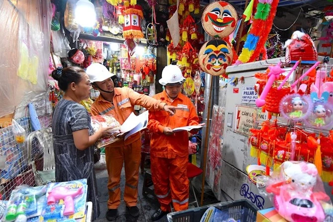 Công nhân EVNHANOI nhắc nhở người dân không tận dụng khu vực gần tủ điện làm nơi buôn bán