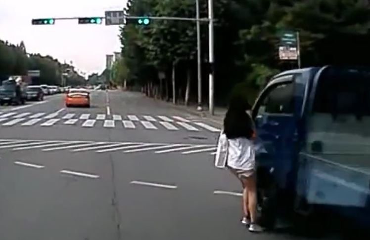 Mải nghe điện thoại khi sang đường, cô gái suýt gặp nạn trước đầu xe tải