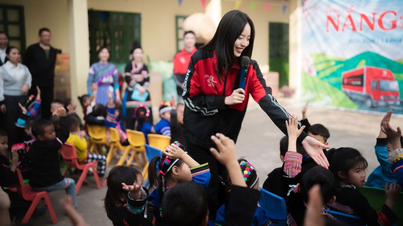 Hoa hậu Thanh Thủy đứng hát giữa sân trường đất, khán giả là học sinh vùng cao