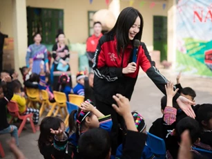 Hoa hậu Thanh Thủy đứng hát giữa sân trường đất, khán giả là học sinh vùng cao