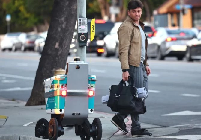 Một người "trông trẻ" robot và robot giao hàng. Ảnh: Futurism.