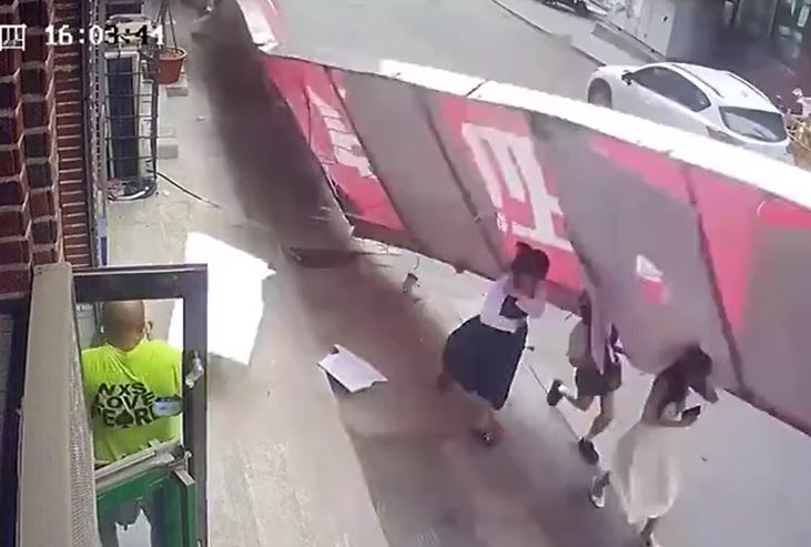 Biển quảng cáo bất ngờ đổ trúng 3 người phụ nữ, đám đông hợp sức giải cứu 