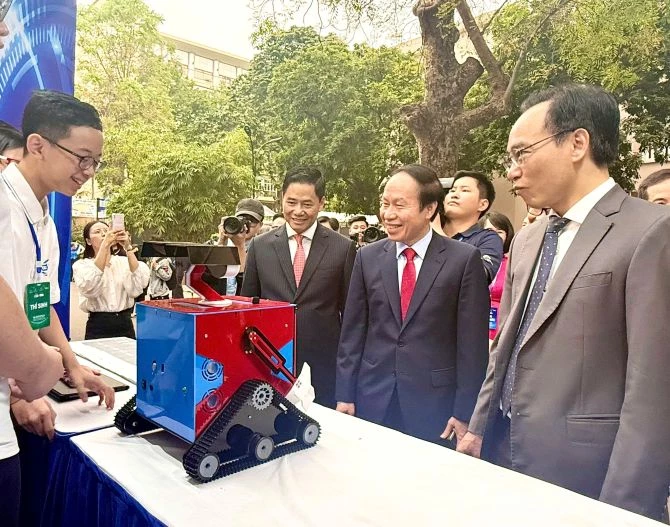 Phó Thủ tướng Lê Tiến Châu lắng nghe các em học sinh giới thiệu Dự án Robot đa nhiệm Homi tại  Ngày hội Khởi nghiệp quốc gia của học sinh, sinh viên lần thứ VIII - năm 2026. Ảnh: Báo điện tử Chính phủ.
