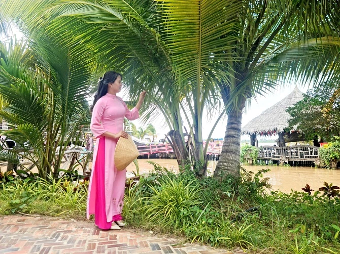 Ảnh 6: Bà Nguyễn Thị Ngọc Yến – Giám đốc điều hành Khu du lịch Cồn &Eacute;n đứng tạo dáng bên hang dừa 3 ngọn