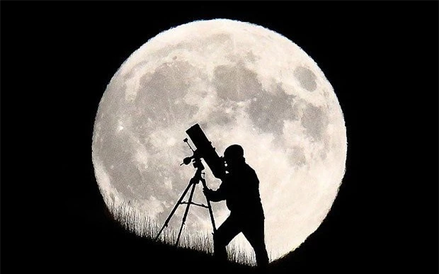 Một nhà thiên văn học in bóng lên mặt trăng khổng lồ ở Brighton (Anh) trong khi chuẩn bị cho sự kiện nguyệt thực toàn phần sắp diễn ra.
