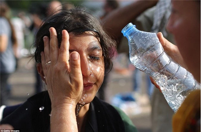 Người di cư dùng nước rửa hơi cay trên mặt cho một bé gái.