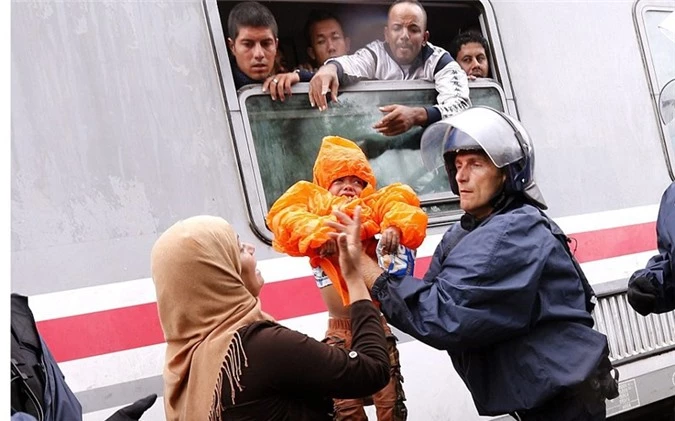 Một cảnh sát giúp đỡ người phụ nữ này bế đứa bé lên một chuyến tàu đến Hungary và Áo từ nhà ga ở biên giới Croatia-Serbia.