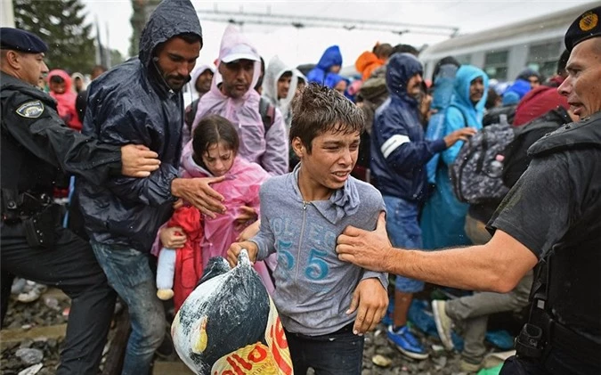 Người tị nạn chen nhau lên tàu ngay cả khi trời mưa. 