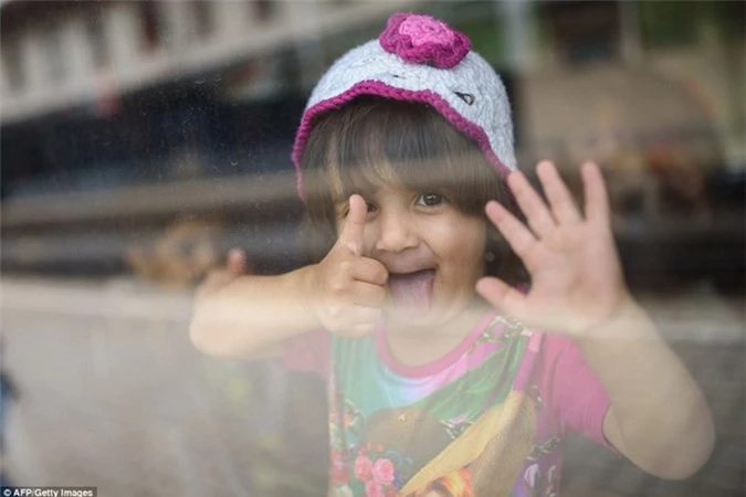 Một bé gái tị nạn sung sướng giơ ngón tay cái sau khi lên tàu thành công.